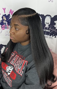 a black woman with long hair sitting on a couch